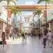 Modern outlet mall entrance with shoppers carrying bags, hinting at designer deals